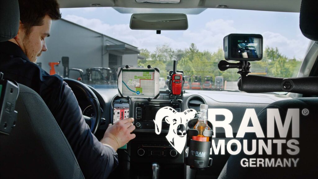 Thumbnail für den Imagefilm RAM Mounts Germany. Ein Mitarbeiter sitzt in einem Auto. Im Interieur sind viele Gadgets vom RAM Mount angebracht. Unteranderem ein Smartphone-Halter, ein Tablet-Halter und ein Getränke-Halter